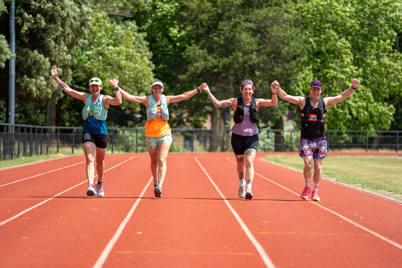 Four Monster Triathlon runners holding hands on the finishing track